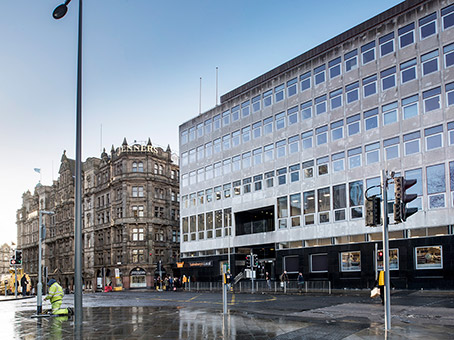 The front of the Regus building is a grey office block, with black fronting at the bottom.  The entrance is to the right of a Sainsbury's Local.